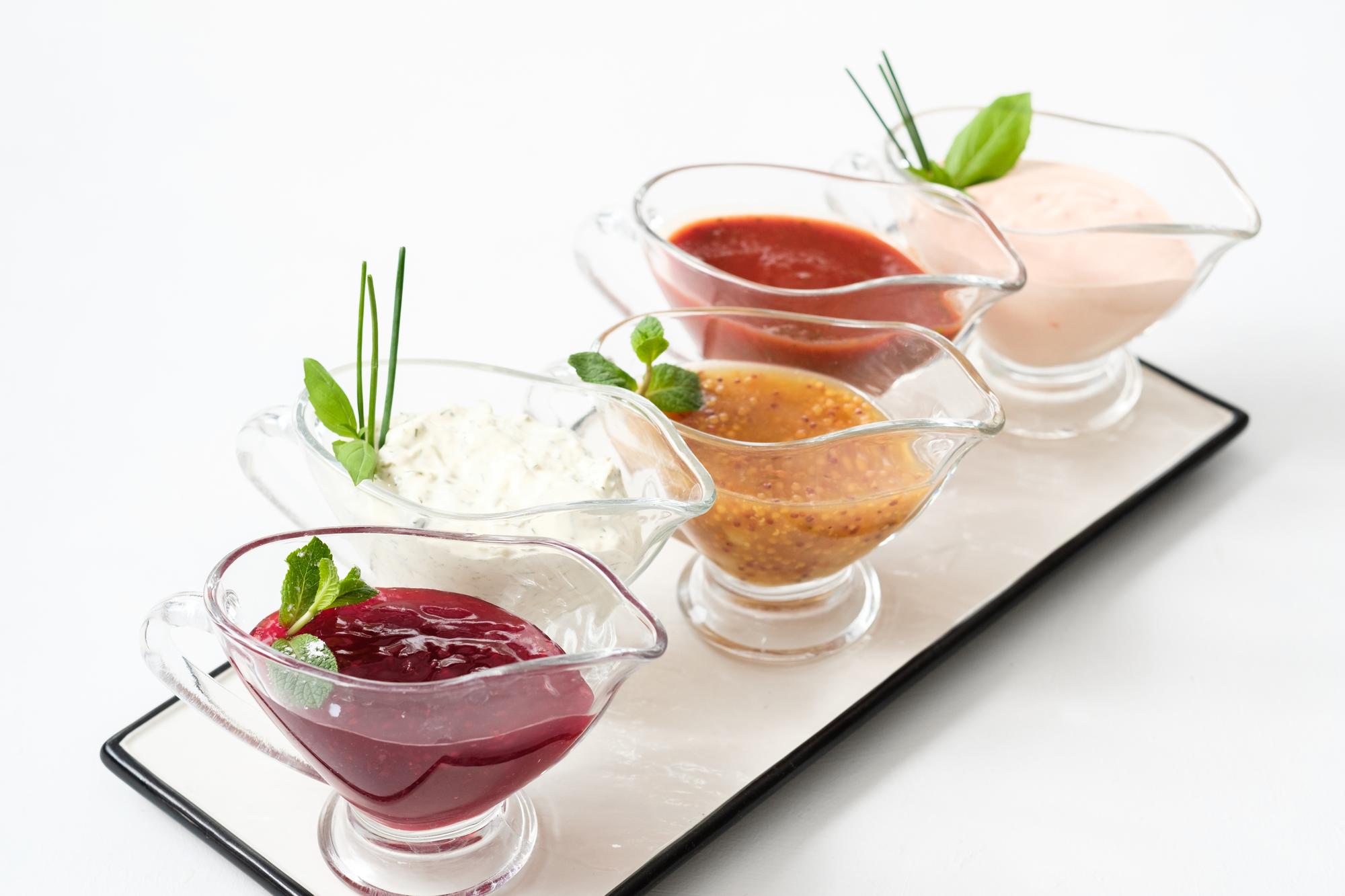 Small tasting plates in a row with textured sauces